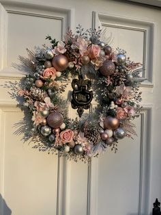 a wreath on the front door decorated with pink and silver ornaments