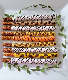 five different types of doughnuts are arranged on a white plate with green leaves