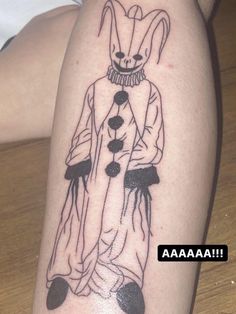 a tattoo on the leg of a person with an evil clown face and legs in black ink