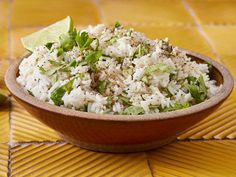 a wooden bowl filled with rice and garnished with cilantro, lime wedges