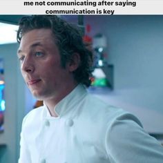 a man with curly hair wearing a white chef's coat and looking off to the side