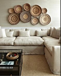 a living room filled with lots of furniture and plates hanging on the wall above it