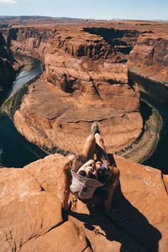 a person sitting on top of a large rock next to a river in the desert