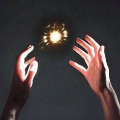 two hands reaching for a glowing object in the dark sky with their palms outstretched toward it