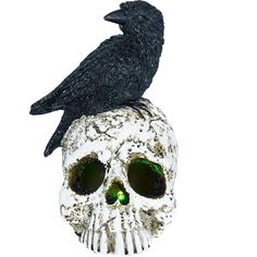 a black bird sitting on top of a white skull with green eyes and beaks