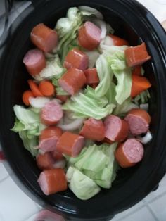 a bowl filled with lettuce, carrots and sausage on top of a table