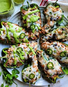 several stuffed peppers on a white plate with green sauce