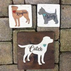 three wooden signs with dogs on them sitting next to each other in front of a brick wall