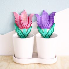 two plastic flowers are sitting in small white pots