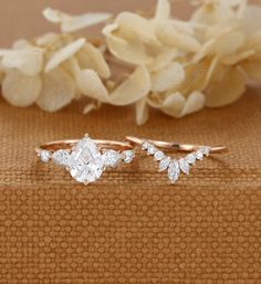 two wedding rings sitting on top of a table next to some white flowers and petals