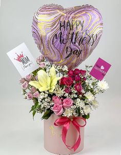 a bouquet of flowers in a pink vase with a heart shaped balloon that says happy mother's day