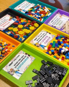 four trays filled with different types of building blocks and magnets on top of a wooden table