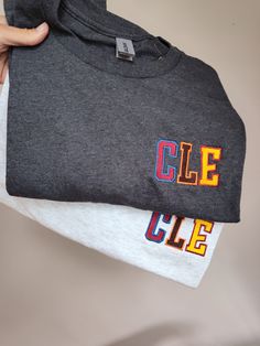 Show your love for your favorite Cleveland teams with this embroidered shirt.  This CLE shirt is the perfect gift for the ultimate Cleveland sports fan! A simple CLE is embroidered in a combination of colors that encompasses the city's baseball, basketball and football teams! Your shirt is embroidered on a soft, unisex Gildan brand t-shirt in your choice of color.   Have a different design in mind?  Great - just send me a message! this design is also available in my shop on a sweatshirt! Sporty T-shirt With Embroidered Graphics For Game Day, Cotton T-shirt With Letter Embroidery For College, Sporty Embroidered Crew Neck T-shirt, Game Day Crew Neck T-shirt With Letter Embroidery, Team-colored Tops With Embroidered Graphics For Fans, Team-colored Cotton Tops With Embroidered Graphics, Game Day Tops With Embroidered Logo, Game Day Cotton Tops With Embroidered Logo, Collegiate Long Sleeve T-shirt With Letter Embroidery