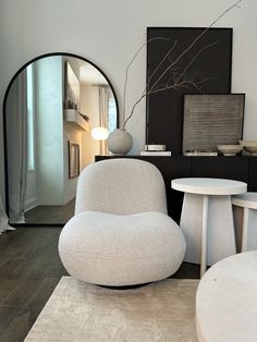 a white chair sitting in front of a mirror on top of a wooden floor next to a table