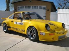 a yellow porsche is parked in front of a garage with a police sign on it