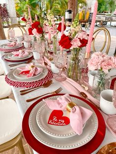 a table set for valentine's day with pink and red flowers