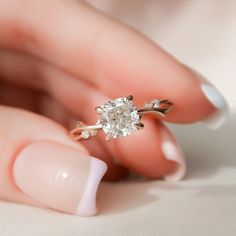 a woman's hand holding an engagement ring with a diamond on the middle finger