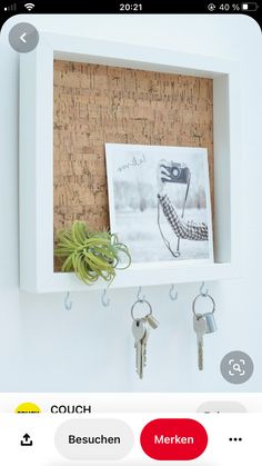 a cork board mounted to the side of a wall with keys hanging from hooks and a photo on it