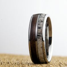 The perfect ring for the outdoorsman. Strong tungsten carbide ring core with inlays of gorgeous figured walnut from a local gunsmith, accompanied by a striking whitetail Deer antler. 8mm wide total width Comfort fit interior Naturally shed antler Handcrafted: Each ring is meticulously handcrafted to ensure a flawless fit. The comfort fit design ensures it's as comfortable as it is striking, whether you're at work or play. 🕊️ Backed by a Lifetime Guarantee: We believe in the quality of our produ Deer Antler Ring, Koa Wood Ring, Mens Wedding Bands Unique, Carbon Fiber Rings, Barrel Rings, Antler Ring, Black Wedding Band, Tungsten Mens Rings, Tungsten Carbide Rings