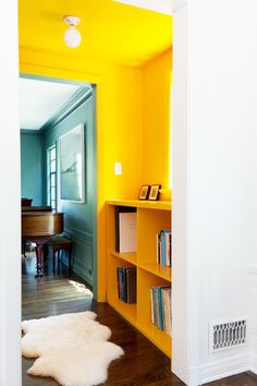 an open door leading to a room with yellow walls and bookshelves on the shelves