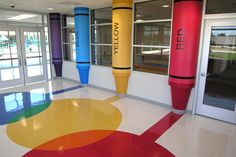 an empty room with brightly painted floors and large colorful tubes on the floor in front of glass doors