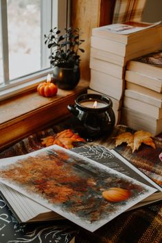 a stack of books sitting on top of a table next to a cup and candle