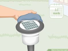 a hand is holding a blue cloth over a solar powered light in front of a calendar