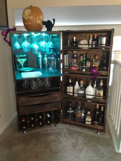 an open cabinet filled with liquor bottles in a living room next to a stair case