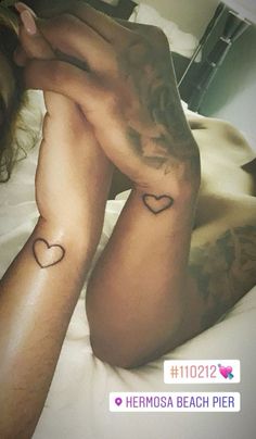 a woman laying on top of a bed with tattoos on her arms and legs,