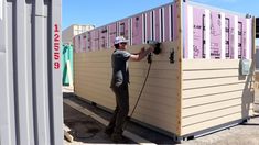 a man standing next to a building that is being built with pink and white siding