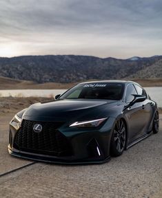 a black sports car parked on the side of a road next to a body of water