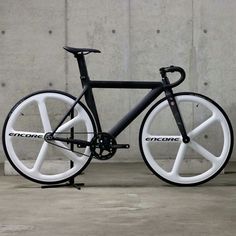 a black and white bicycle parked in front of a concrete wall