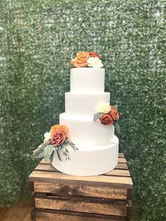 a three tiered white wedding cake with orange flowers