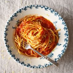 a plate of spaghetti with sauce and a fork in it on a white tablecloth