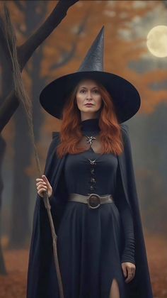 a woman dressed as a witch holding a stick and wearing a black dress with long sleeves