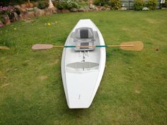 a white canoe sitting on top of a lush green field