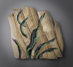 three pieces of art made out of wood with green and blue designs on them, sitting side by side