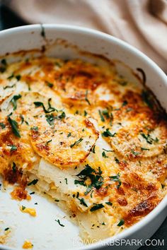 a close up of a casserole in a pan with cheese and herbs on top