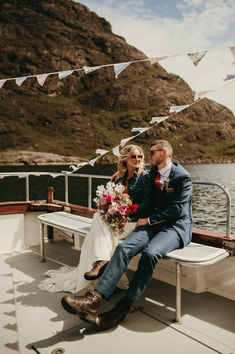 a bride and groom sitting on a boat in front of some bunting streamers