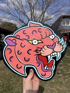 a hand holding up a sticker with an image of a pink tiger on it