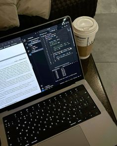 an open laptop computer sitting on top of a table next to a cup of coffee