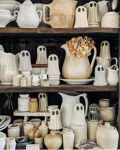 a shelf filled with lots of white dishes and vases