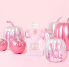 pink and silver pumpkins with the word boo on them are next to a perfume bottle