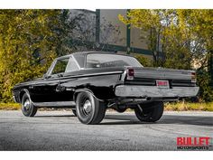 an old black car is parked on the street