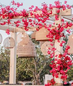 an outdoor dining area with flowers on the table and hanging baskets in the air above it