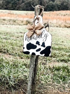 a wooden sign with a bow hanging from it's side on a pole in the grass