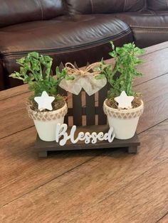 two potted plants are sitting on a small wooden sign that says, be blessed