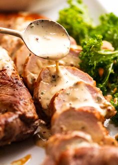 a plate with meat, broccoli and sauce being drizzled on it