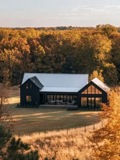 a large black house surrounded by trees in the fall