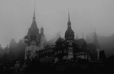 an old castle in the fog with steeples on it's sides and spires